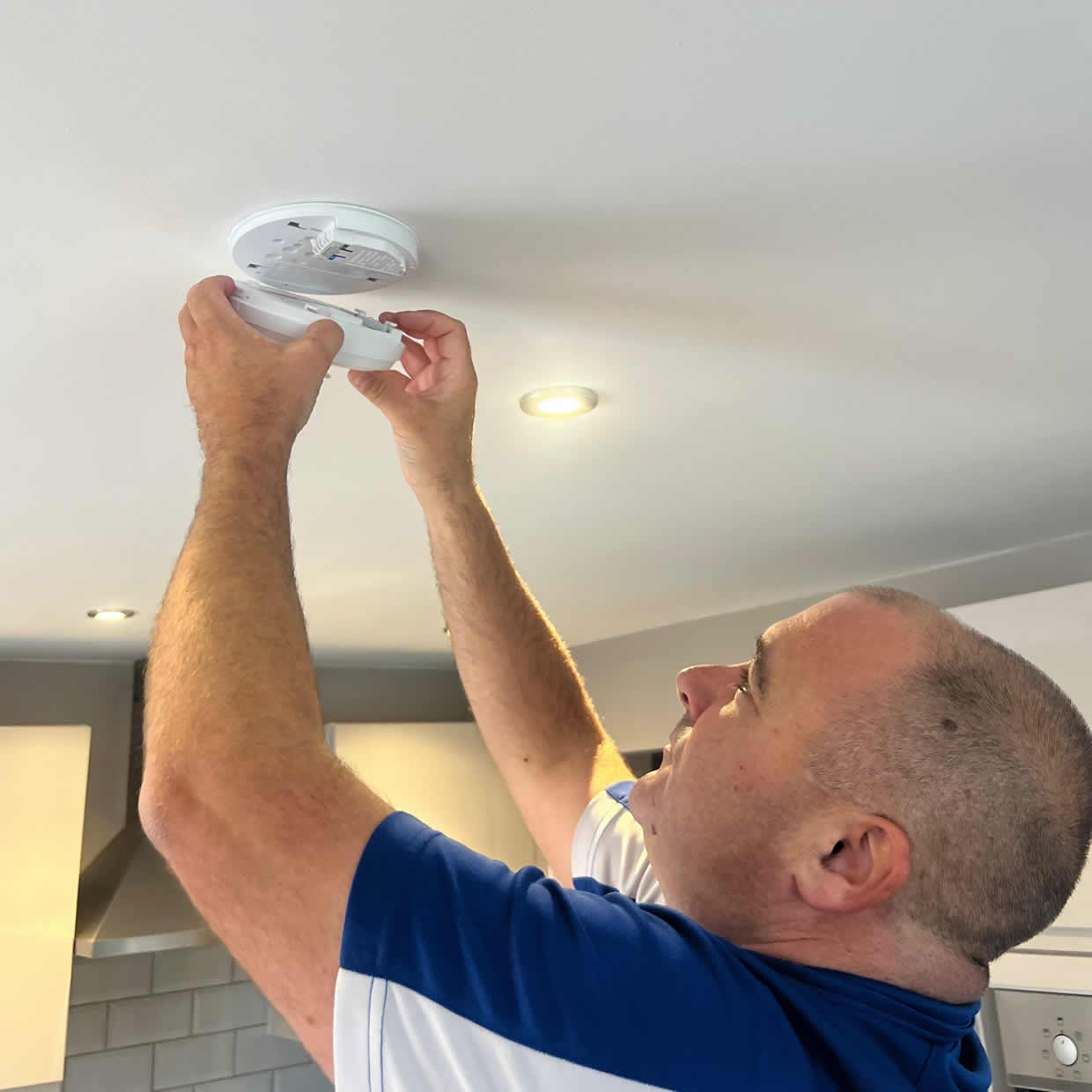 Smoke alarm installer fitting a bedroom-safe alarm in a Manchester property
